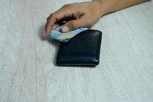 homme tenant des billets en roupies sur un portefeuille noir photo