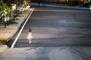 vue arrière arrière d'une fillette asiatique faisant du jogging dans le parc le soir d'été ou de printemps. l'enfant fait du sport pour une bonne santé. enfants de 5 ans. photo