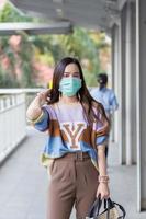 une belle femme asiatique marchant dans la ville porte des chandails colorés, des cheveux longs et des masques médicaux dans un nouveau concept normal de pollution pm2,5 et de soins de santé. photo