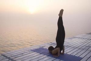 jeune femme posant dans le yoga asans, fond de mer du matin photo