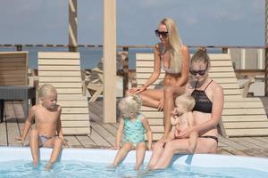 famille heureuse s'amusant dans la piscine bleue photo