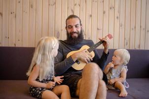 père barbu avec des enfants jouent sur ukulele indoor photo