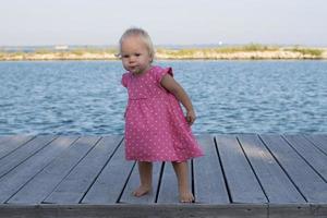 petite fille en robe rose près de la rivière photo