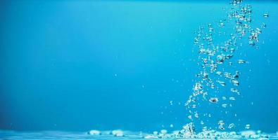 image de fond abstrait de bulles dans l'eau. eau propre avec des gouttelettes d'eau et des vagues. eau douce un verre avec fond bleu bulles. photo