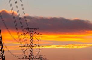 poteau électrique à haute tension et lignes de transmission le soir. pylônes électriques au coucher du soleil. puissance et énergie. conservation de l'énergie. tour de réseau haute tension avec câble métallique à la station de distribution. photo