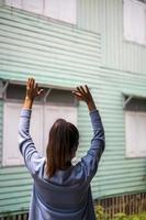 derrière la femme se tenait les mains levées près du mur de la maison en bois. photo