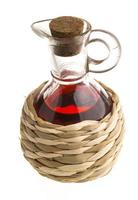 Petite carafe avec du vinaigre de vin rouge isolé sur le blanc photo