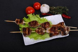 brochettes de kebab de porc dans l'assiette avec des feuilles de salade et des tomates photo