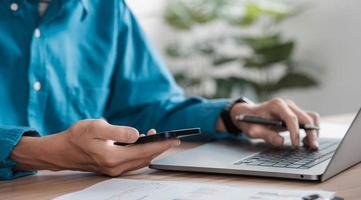 homme d'affaires assis au travail à l'aide d'un téléphone portable, dactylographie, ordinateur, chat, téléphone portable, ordinateur portable, contact avec les clients sur le lieu de travail, idées de planification, investisseurs en ligne. photo