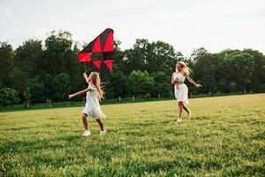 courir ensemble. mère et fille s'amusent avec le cerf-volant sur le terrain. belle nature photo