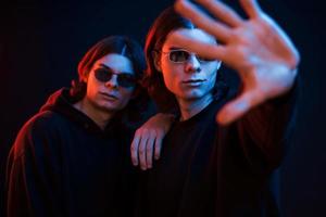 je te protègerai. portrait de frères jumeaux. tourné en studio dans un studio sombre avec néon photo