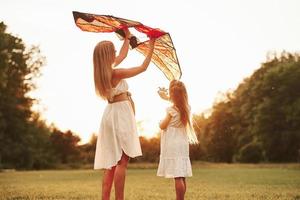 continuez à le tenir comme ça. mère et fille s'amusent avec le cerf-volant sur le terrain. belle nature photo