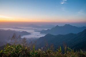 le lever du soleil à la montagne avec le brouillard et les nuages le recouvrent. photo