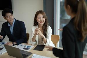 une équipe de concepteurs de groupes de travail d'entreprises diverses avec une femme asiatique leader discutent des données statistiques du rapport financier de la paperasserie, prévoient de travailler sur un projet commun. remue-méninges, concept d'activité d'information photo