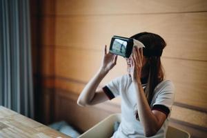 ravie d'une jeune femme asiatique portant un casque vr, profitant de passer du temps libre dans la réalité virtuelle. femme multiraciale millénaire excitée jouant à la simulation de jeu en ligne, testant l'achat moderne. photo