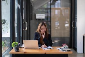 femme d'affaires asiatique ou agent immobilier travaillant avec un ordinateur portable à son bureau photo
