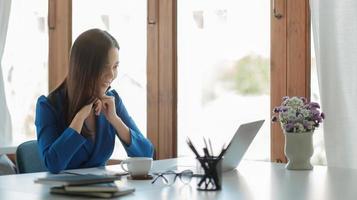 heureuse jeune femme d'affaires asiatique utilisant un ordinateur portable pour saluer son partenaire lors de la vidéoconférence avec son équipe photo