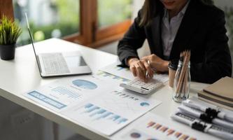 une femme d'affaires ou comptable travaillant dans la finance et la comptabilité analyse le budget financier à partir d'un rapport sur la paperasserie avec une calculatrice et un ordinateur portable au bureau photo