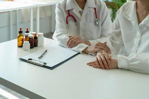 une femme médecin asiatique en uniforme médical blanc consulte une patiente dans un hôpital privé. femme thérapeute parle parler avec une cliente lors d'une consultation en clinique photo