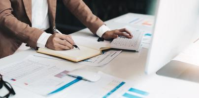 photo recadrée d'une femme écrivant faisant une liste prenant des notes dans un bloc-notes travaillant ou apprenant sur un ordinateur portable à l'intérieur - cours éducatif ou formation, séminaire, concept d'éducation en ligne