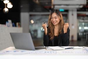 portrait d'une jeune femme asiatique heureuse d'affaires célébrant le succès avec les bras levés. expression positive, succès dans le concept d'entreprise photo