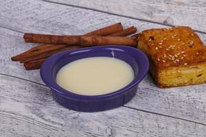 lait concentré dans le bol avec sinnamon et pâtisserie photo