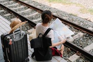 jeune femme voyageuse avec sac à dos à la recherche de carte en attendant le train, routard asiatique sur la plate-forme ferroviaire à la gare. vacances, voyage, voyage et été concept de voyage d'été photo