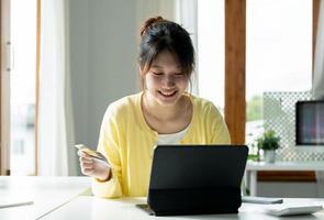 gros plan sur une fille tenant une carte de crédit bancaire, faire des achats en ligne à l'aide d'un téléphone portable, acheter des biens ou commander en ligne, entrer des comptes bancaires et des détails dans l'offre bancaire en ligne. photo