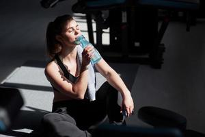 rafraîchissant avec de l'eau. photo d'une superbe femme blonde dans la salle de sport le week-end