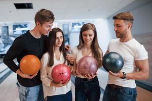 debout ensemble. de jeunes amis joyeux s'amusent au club de bowling le week-end photo