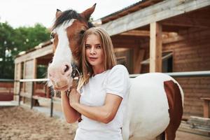 animal de couleur marron et blanc. femme heureuse avec son cheval sur le ranch pendant la journée photo