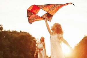 humeur joyeuse. mère et fille s'amusent avec le cerf-volant sur le terrain. belle nature photo