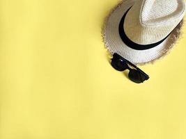 chapeau tissé et lunettes de soleil sur fond de couleur jaune pastel été photo