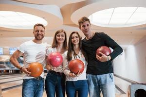 quatre personnes positives. de jeunes amis joyeux s'amusent au club de bowling le week-end photo