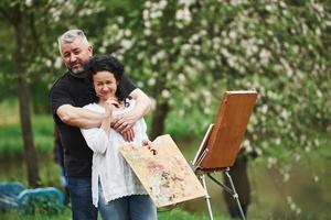 profiter du week-end. un couple d'âge mûr a des journées de loisirs et travaille ensemble sur la peinture dans le parc photo