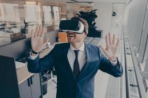 un homme d'affaires sorti se tient à l'intérieur du bureau après avoir terminé sa journée de travail dans un casque vr de réalité virtuelle photo