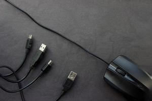souris d'ordinateur noire avec câbles usb et mini usb sur fond noir avec place pour votre conception. photo