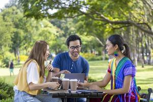 un groupe d'étudiants se réunit et travaille sur une thèse et un projet à l'extérieur dans le jardin du campus universitaire pendant l'été photo