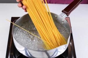 femmes cuisinant des spaghettis dans une casserole d'eau bouillante dans la cuisine photo