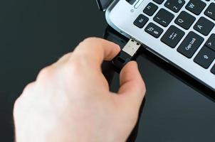 main brancher le lecteur flash USB sur un ordinateur portable. photo
