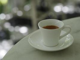 Café expresso chaud dans une tasse blanche posée sur une table en marbre photo