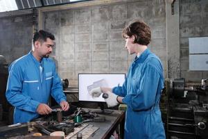 deux ingénieurs professionnels de l'industrie partenaires dans les uniformes de sécurité des travaux de métallurgie discutent du dessin mécanique dans un moniteur, des tours et un atelier de pièces de production dans une usine de fabrication. photo