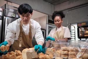 deux jeunes amis et partenaires de démarrage de pâte à pain et de pâtisseries occupés à des travaux de boulangerie maison tout en préparant des commandes quotidiennes, en emballant et en livrant dans une boulangerie, petit entrepreneur. photo