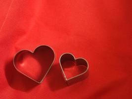 moules à pain en forme de coeur en acier inoxydable sur fond rouge en tissu, amour saint valentin pour copier la carte de texte, arrière-plan photo
