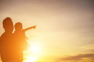 le père a emmené le bébé apprendre à marcher au coucher du soleil. photo