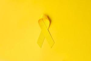 ruban jaune sur fond jaune pour soutenir les personnes vivant et malades. journée de prévention du suicide en septembre, mois de sensibilisation au cancer infantile et concept de journée mondiale contre le cancer photo