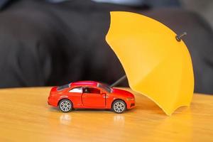 couverture de parapluie jaune ou jouet de voiture rouge de protection sur la table. concept financier, monétaire, de refinancement et d'assurance automobile photo