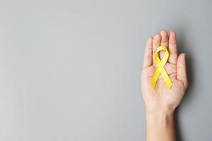 mois de sensibilisation au cancer infantile, au sarcome, aux os, à la vessie et à la prévention du suicide, ruban jaune d'or pour soutenir les personnes vivant et malades. santé des enfants et concept de la journée mondiale du cancer photo