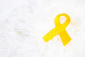 ruban jaune sur fond blanc pour soutenir les personnes vivant et malades. journée de prévention du suicide de septembre, concept de mois de sensibilisation au cancer du sarcome et au cancer infantile photo