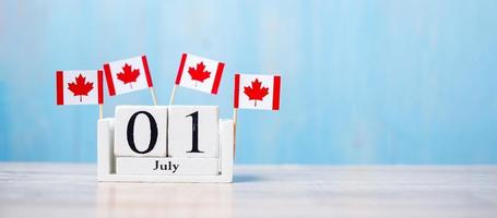 calendrier en bois du 1er juillet avec des drapeaux miniatures du canada. concepts de la fête du canada et de la fête du canada photo
